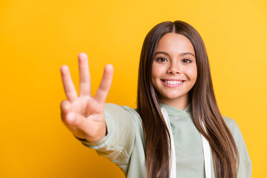 Photo of charming sweet child girl dressed casual green outfit showing you three fingers isolated yellow color background