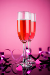 Studio photo of pink champagne on pink background and reflective surface.