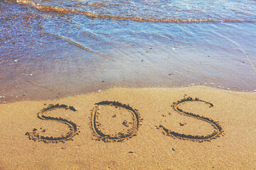 The word SOS on the beach sand