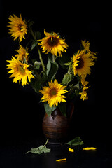 Beautiful bouquet of sunflowers in vase on a black table over black background