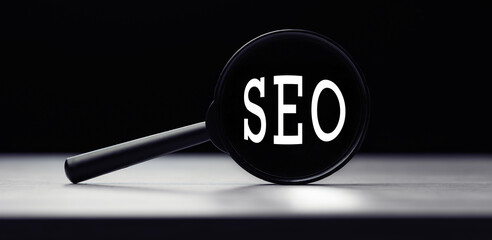 Magnifying glass with the word SEO - search engine optimization on table
