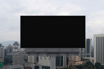 Blank black road billboard with Kuala Lumpur cityscape background at day time. Street advertising poster, mock up, 3D rendering. Front view. Concept of marketing to promote or sell services or ideas.