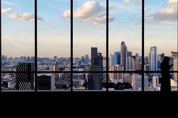 Naklejka na ściany i meble silhouette outline of women tourist taking pictures of city skyline from an observatory. sunset at modern urban business district. steel frame rose windows architectural element design.