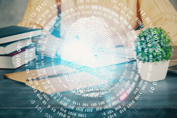 Blue fingerprint hologram over hands taking notes background. Concept of security. Double exposure
