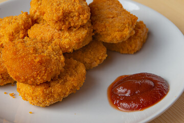 Chicken nuggets on a white plate, with ketchup