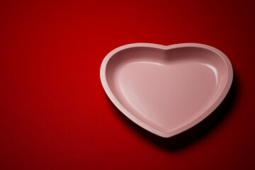 Studio photo of heart shaped plate on deep red background.