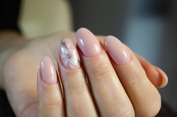 Hands of a young woman. The nails are covered with a light colored gel Polish with a delicate design. Manicure ideas.