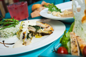 Fillet of white fish sea bass, cod stuffed with greens and rice on the table in the restaurant.