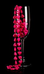 Obraz premium Studio photo of a champagne glass with pink necklace inside on black background.