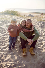 family with a son and daughter and a dog sit on the sand