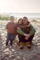 family with a son and daughter and a dog sit on the sand