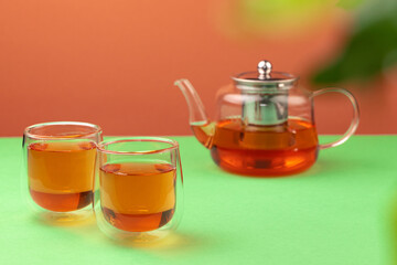 Glass teapot and two glass cups with tea