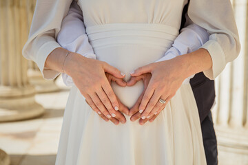 Cropped image of beautiful pregnant woman and her handsome husband hugging the tummy