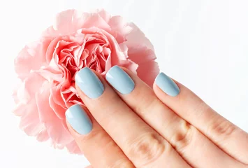Female hand with manicure on flower on white background, top view