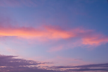 View of the sky in the evening at sunset with a dark cloud and bright orange glow from the sun. Landscape concept, background.