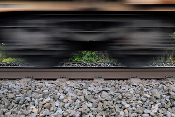 Gleisbett mit Schotter und Gleis und Ausschnitt von vorbeifahrendem G&uuml;terzug mit Bewegungsunsch&auml;rfe - Stockfoto