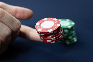 Poker chips of green and red color on a blue background the hand puts them