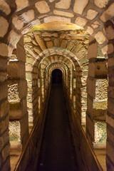 Fototapeta na wymiar Tunnel with stone arches in the catacombs of Paris, France