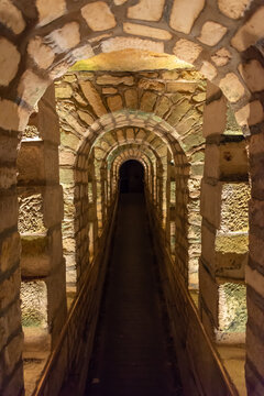 Tunnel with stone arches in the catacombs of Paris, France