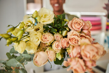 Happy young man holding blomming bouquet in flower shop