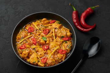 Chicken Handi in black bowl on dark slate table top. Murgh Chicken is indian cuisine curry masala dish. Asian food and meal.