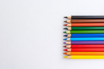 Horizontal side situated colored pencils on a white isolated background with copy space. Creativity palette for sketching and drawing. Multicolored graphic equipment
