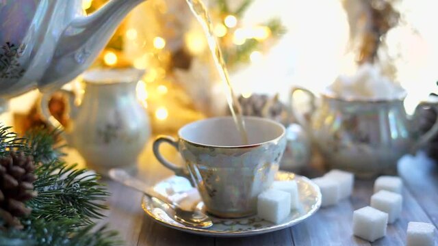 Traditional English tea is poured into a cup from a Chinese porcelain set in a Christmas decor.