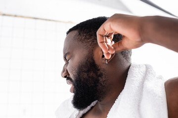 Obraz premium portrait of afro-american man cleaning ears with pain