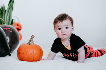 Fototapeta premium beautiful baby girl in halloween costume at home, sitting on bed with Halloween decoration, Lifestyle indoors