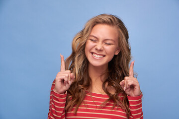 Fototapeta premium Close up photo of an attractive excited girl with straight index fingers eyes closed and tongue showing empty space show novelty banner dressed in red clothes with yellow stripes on a blue background