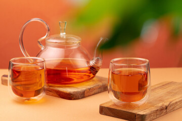 Glass teapot and two glass cups with tea