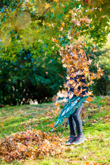 cute little girl playing collecting leaves in the garden