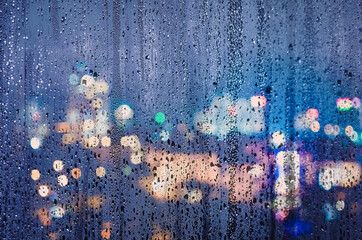 A view of city lights seen through a rainy covered window