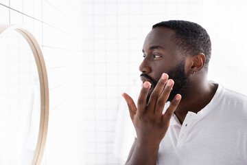 afro-american man applying cure for strengthening beard growth