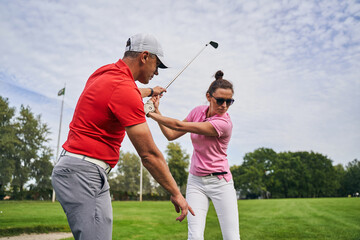 Golfer mastering a swing technique assisted by her coach