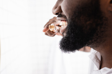 close-up view of afro-american man brushing teeth with bamboo toothbrush