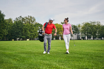 Female golfer looking at her pleased trainer