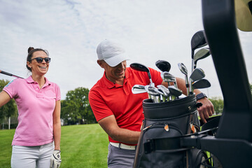 High-spirited sporty lady standing behind her golf instructor