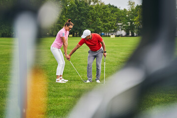 Smiling beginner golfer training with her personal coach