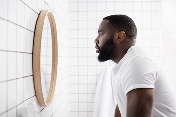 side view of serious afro-american man looking in mirror