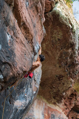 Athletic climber moves on colorful masses of rock.