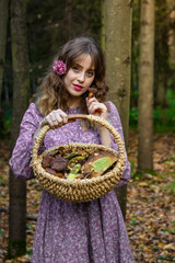 Girl in the forest in a dress with a floral pattern with a basket full of mushrooms. Photo in retro style.