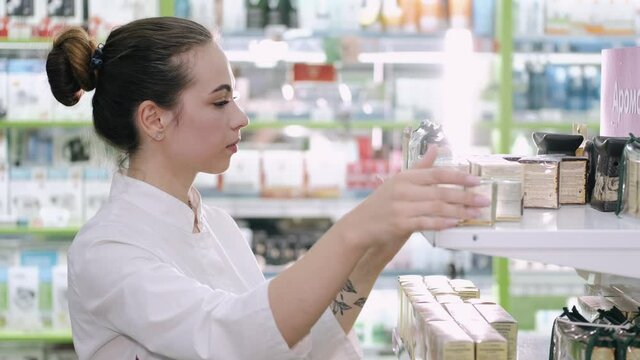 A female pharmacist is looking at some products on the shelf. She is checking the medicines.