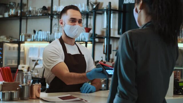 A customer is paying by mobile phone card while buying coffee in a craft pocket during quarantine indoors