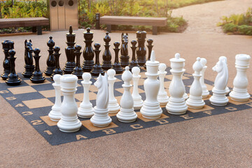 Outdoor chess board with big plastic pieces. Giant size chess in public area zone. Close up big...