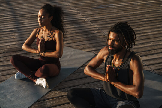 Calm afro american couple doing yoga exercises