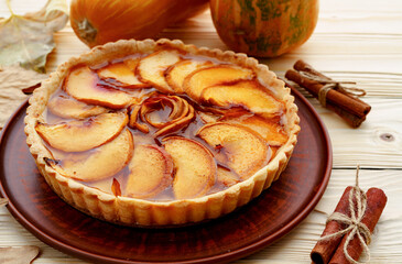 Apple tart pie on table with pumpkin and dry leaves