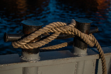 Mooring ropes coiled on ferry deck. Strong braided ropes for anchoring the boat in sunset light. Close up. Blue water