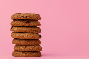 Stacked chocolate chip cookies against pink background