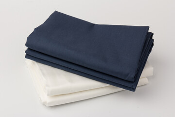 Stack of clean white and blue bed sheets on white  background, closeup.